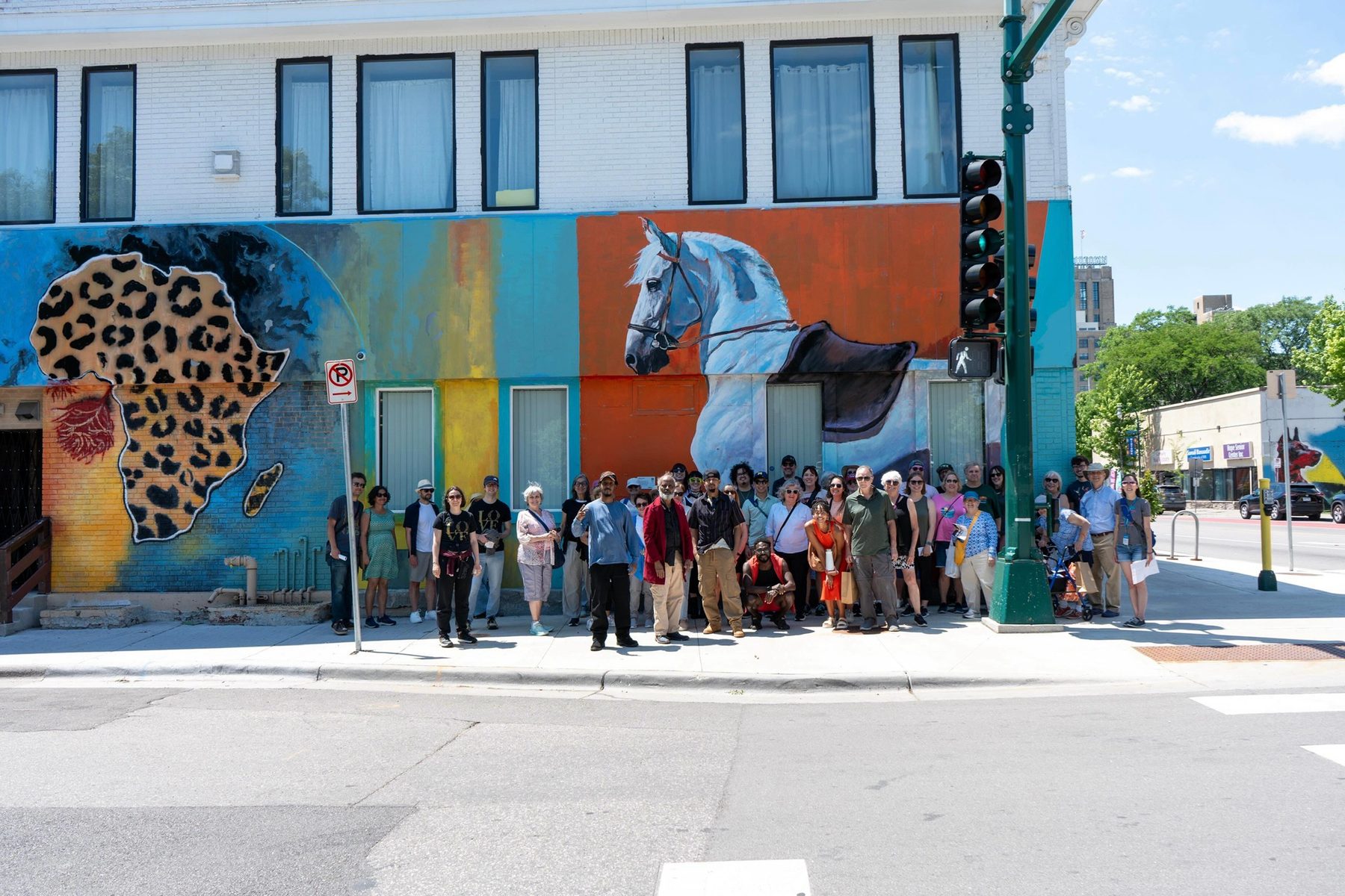 The community gathered in front of the leopard and horse mural at The East Corner on Lake Street